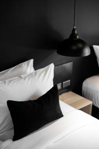 查汶BedTime Hotel Samui的一张带黑白枕头的床和黑灯