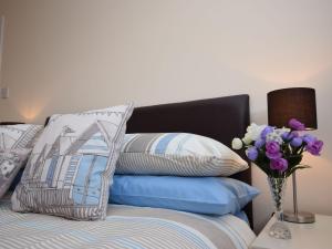 Marhamchurch2 Bed in Widemouth Bay 40636的床上有枕头,花瓶上有鲜花