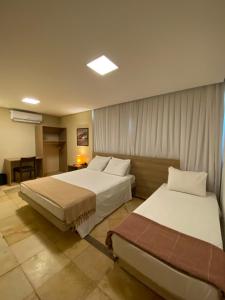 阿奎拉兹Pousada Tropical Ilhas的酒店客房设有两张床和一张桌子。