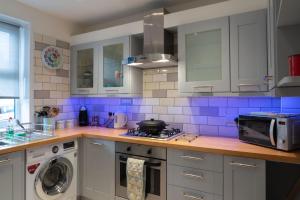 布莱顿霍夫Sunny Queens Park Home - Garden & Private Parking的厨房配有白色橱柜和蓝色瓷砖
