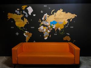 阿拉木图Atlas Hotel的一张橙色的长沙发,墙上挂着一张世界地图