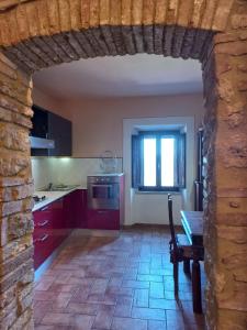 波马兰切Casa Marzocco的厨房配有红色橱柜、桌子和窗户