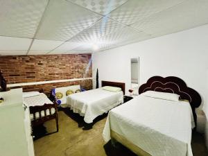 康塞普西翁德阿塔科Entre tejas的一间卧室设有两张床和砖墙