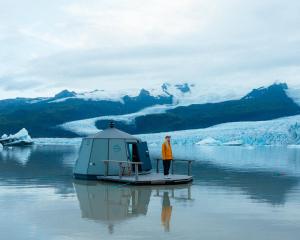 霍夫Fjallsarlon - Overnight adventure的站在水中小船上的人