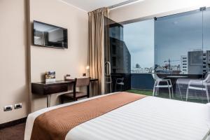 利马皮拉尔米拉弗洛雷斯酒店的酒店客房设有一张床、一张书桌和一个阳台。