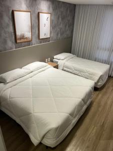 巴拉奈里奥-坎布里乌达斯阿莫瑞卡斯酒店的配有白色床单的酒店客房内的两张床