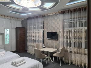 撒马尔罕Nazarxan Hotel的一间酒店客房,设有两张床、一张桌子和一台电视机