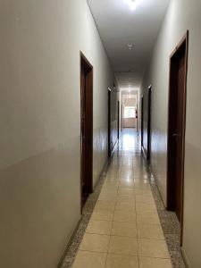 MatipóHotel Boa Vista的空的走廊,有门,铺着瓷砖地板