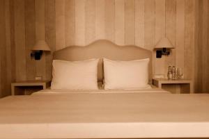 米克诺斯城卡洛格拉旅馆的一间卧室配有一张带白色枕头的床和两盏灯。