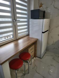 华沙Krucza Apartament的厨房配有2张红色凳子和冰箱