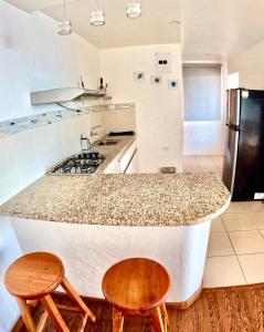 巴克里索莫雷诺港Suite Cielo, Discover the magic of Galapagos的厨房配有带2把椅子的柜台和冰箱。