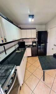 安托法加斯塔Casa en condominio jardines del norte Antofagasta.的厨房配有白色橱柜和黑色冰箱。