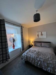 卡伦德Newly refurbished flat - Callander的一间卧室配有一张床,窗户配有花瓶