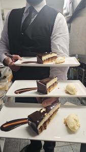 梅努斯53 Luxury Rooms的厨师把两盘甜点盘子托起来