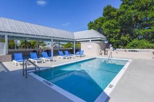 基韦斯特New Casa Caribe by Brightwild- Two-Story Condo Rooftop Pool的一座带蓝色椅子的游泳池,位于大楼旁