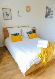 讷伊-普莱桑斯Cosy Casa entre Paris et Disney的一张带白色床单和黄色枕头的床