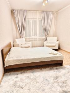 阿拉木图Квартира的一间卧室配有一张床、两把椅子和一个窗户