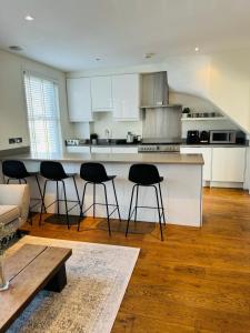 伦敦Stunning Flat in Chiswick的厨房配有白色橱柜和酒吧凳子