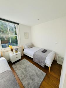 伦敦Stunning Flat in Chiswick的一间白色卧室,配有两张床和窗户