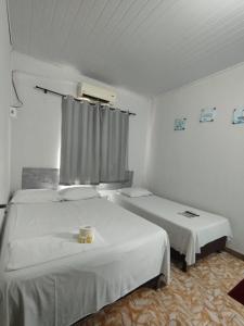 库亚巴Hotel Perola Ltda的白色的客房设有两张床和窗户。