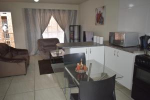 杰米斯顿Apartment in Germiston (Johannesburg)的厨房以及带玻璃桌的起居室。
