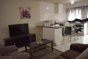 杰米斯顿Apartment in Germiston (Johannesburg)的带电视的客厅和带桌子的厨房。