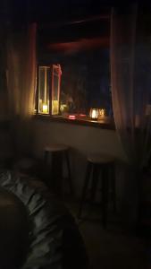 卡尔维chambre love romantique avec spa privée的一间设有一张桌子、两张凳子和窗户的黑暗客房
