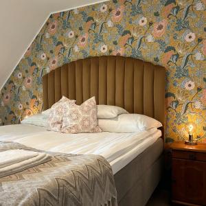 哈尔姆斯塔德Halmstad Gårdshotell的一间卧室配有一张带花卉壁纸的大床