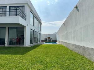 谢内吉亚区Casa de Campo Paz y Bien - Cieneguilla的一座白色的大房子,有一码草