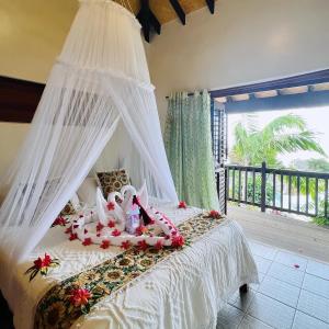 塔纳岛塔纳常青旅游度假村的一间卧室配有一张带天蓬的白色床