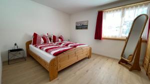 克洛斯特斯Ferienwohnung mit idyllischer Aussicht的一间卧室配有一张带红色枕头的床和一扇窗户