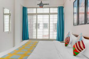 LohogaonOYO Home Dazzling Studios Near Airport Near Pune Airport的一间卧室设有大窗户和蓝色窗帘