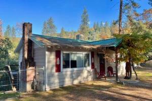 奥克赫斯特Red Door Cottage Fireplace bbq 12 mi to Yosemite的一座白色的小房子,设有绿色屋顶