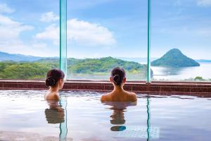 上天草Ooedo Onsen Monogatari Amakusa Hotel Kameya的两个女孩坐在游泳池里,望着水面