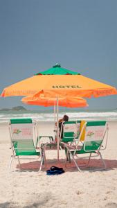 瓜鲁雅Hotel Ilhas do Caribe - Na melhor região da Praia da Enseada的海滩上的两把椅子和一把遮阳伞