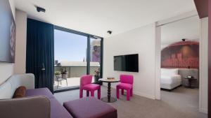 悉尼悉尼蓝塞瑞拉莫特酒店的酒店客房配有粉红色的椅子、桌子和电视。
