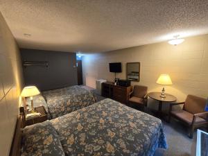 史密瑟斯卡普里汽车旅馆 的酒店客房带两张床和一张桌子以及椅子。