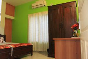 科钦Oshin Home Stay的一间卧室设有绿色的墙壁、一张床和橱柜