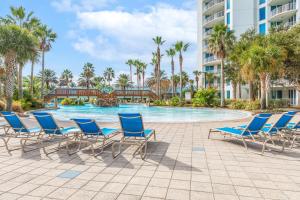 德斯坦Entire Condo - Palms of Destin Paradise的度假村的游泳池设有蓝色椅子和棕榈树