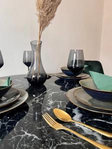 维也纳Luxus Apartment的黑色桌子,上面有盘子和玻璃杯,花瓶