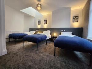 利物浦Goodison Accommodation的配有蓝色床单的客房内的三张床