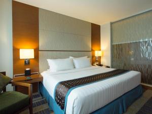 宿务Lex Hotel Cebu的酒店客房带一张大床和一把椅子