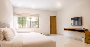 勒吉安D'Green Kuta Managed by ARM Hospitality的白色卧室设有一张大床和电视。