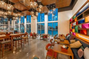 绥和市Wink Hotel Tuy Hoa Beach - 24hrs stay & Rooftop Pool Bar的餐厅设有桌椅和大窗户。