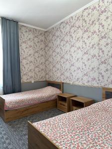 奥什Sunny Hostel的花卉壁纸客房内的两张床