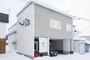 东川町The Peak Villa Suite Hokkaido的雪地里设有车库的白色建筑
