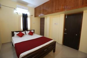 库姆巴科纳姆ABOORVA GRAND INN _ HOMESTAY_ ROOMS _RESORT _HOTEL IN KUMBAKONAM的一间卧室配有一张带红色枕头的床和一扇门