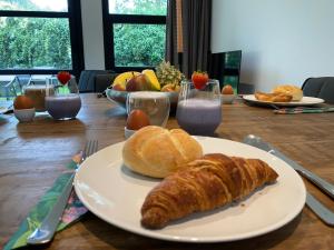 埃尔默洛Luxe 4- persoons Veluwelodge met hottub in Ermelo!的一张桌子上放着一盘面包和羊角面包