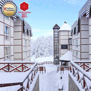 科帕奥尼克科拉勒维卡达西酒店的一座带时钟的建筑的雪覆盖的庭院