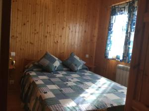 坎德拉里奥Casitas Cinco Castaños的一间卧室配有一张带木墙和窗户的床。